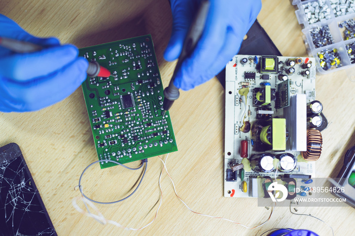 Technician engineer in workshop. Repairman is checking circuit board of electronic device.