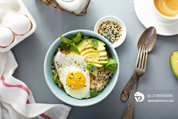 Savory oatmeal with sunny side up egg and avocado for breakfast overhead