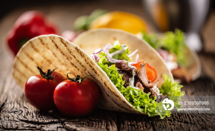 Open meat and veg tortilla on a rustic wooden board