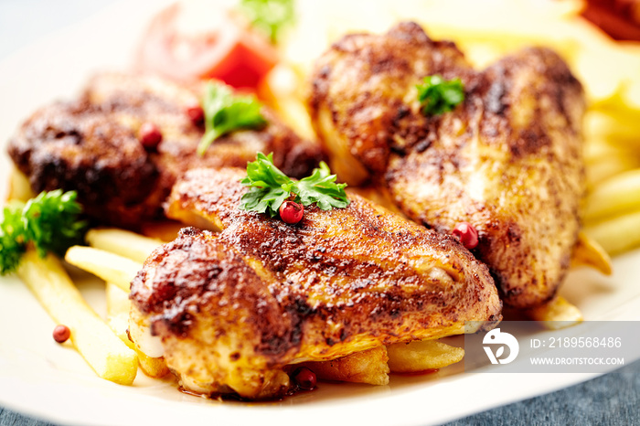 Spicy chicken wings with french fries and tomatoes. Close up.