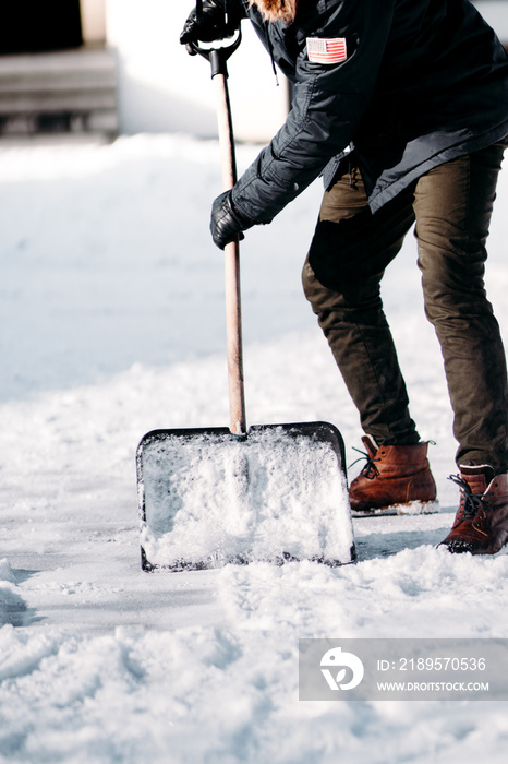 caucasian adult cleaning snow from sidewalk and using snow shovel after heavy snowstorm