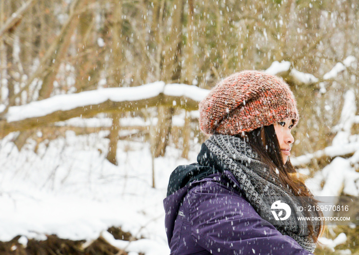 雪地里戴针织帽子和围巾的年轻女子