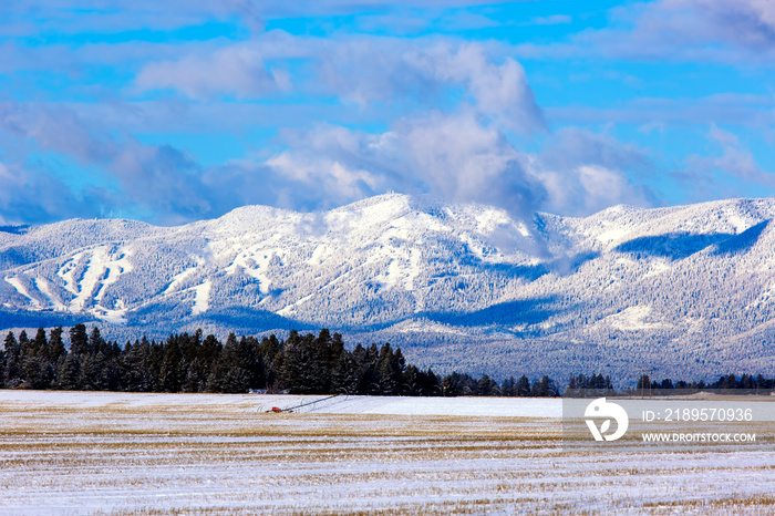 Scenic fresh snow on moutains and farm field with irrigation wheel move in Flathead Valley, Montana