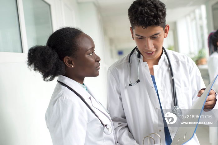 Black woman and white male doctors. A pair of young doctors of mixed race in white coats with a fold