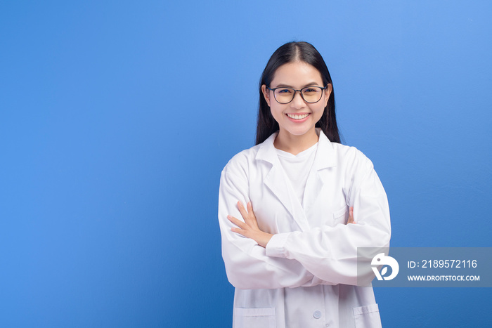 Young female ophthalmologist with glasses holding eye chart over blue background studio, healthcare 