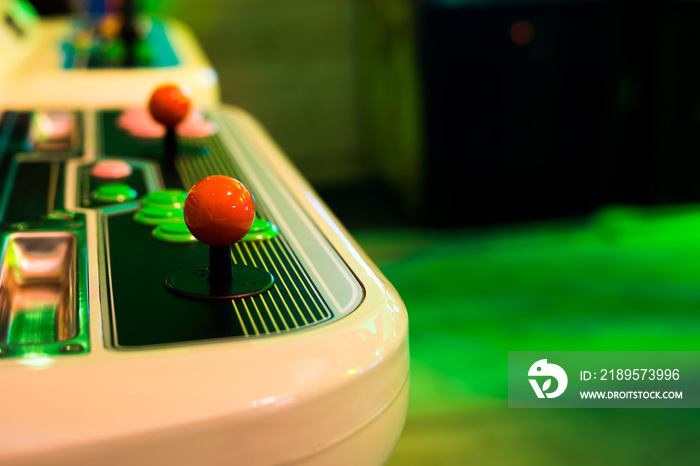 Detail of a red rounded joystick and buttons on an old arcade game in a gaming room