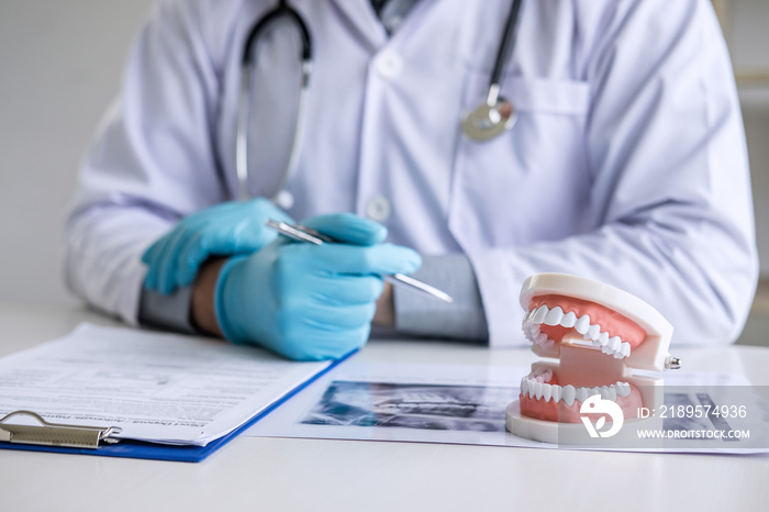 Male doctor or dentist working with patient tooth x-ray film, model and equipment used in the treatm