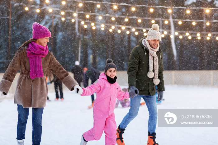 christmas, family and leisure concept - happy mother, father and daughter at outdoor skating rink in