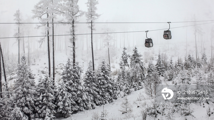 Two chairlift cabins passing each other on gray winter overcast day. Tatranska Lomnica ski resort, S