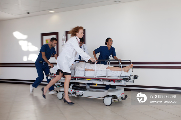 Doctors and nurses rushing patient on stretcher in hospital corridor