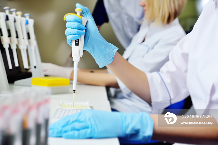 A scientist in a medical laboratory with a dispenser in his hands is doing an analysis