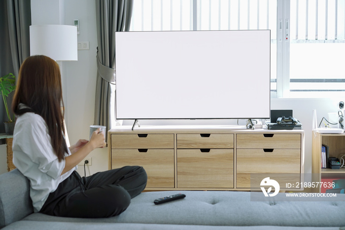 女人在沙发上放松时看白色屏幕电视。白色屏幕电视用于蒙太奇画面。