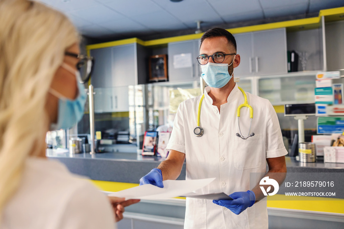 Medical worker in sterile uniform, with rubber gloves and face mask on giving corona virus test resu