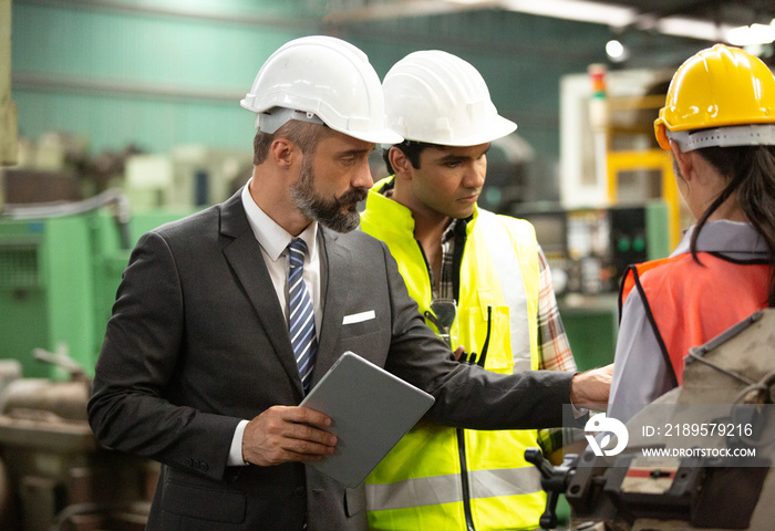 Business director and Mechanic engineer checking and discussing at factory shop floor.