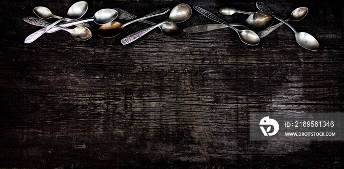 老式餐具——在古老的木制背景上的勺子、叉子和刀子。
