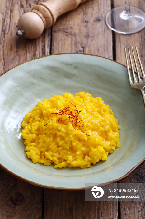 risotto allo zafferano tradizionale italiano su sfondo tavolo di cucina rustico