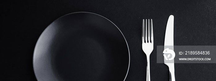 黑色背景的空盘子和银器，节日晚餐的高级餐具，极简主义