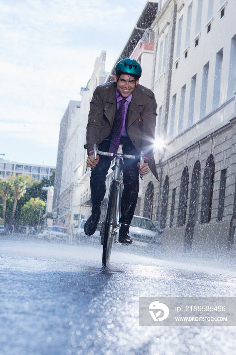 微笑的商人在下雨的城市街道上骑自行车