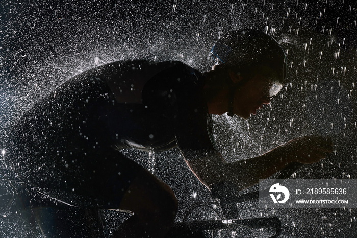 triathlon athlete riding bike fast on rainy night