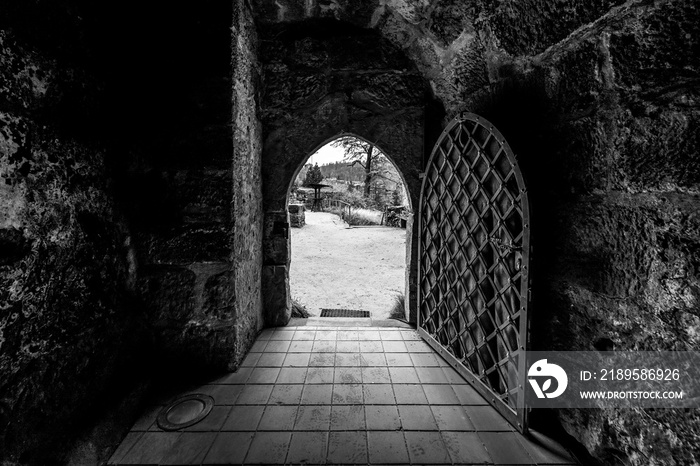 Arched entrance with metal gates to the fortress. Black and white.