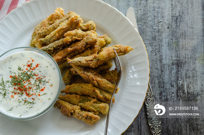 The crispy fried okra in container and spicy yogurt sauce