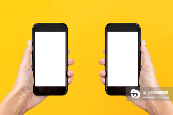 Two hands holding mobile phones on yellow background with empty screens