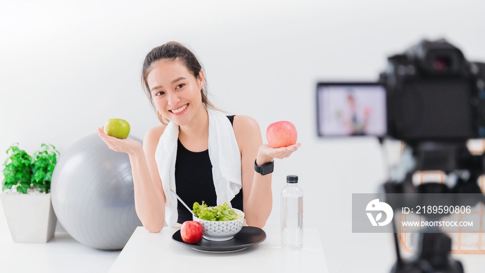 Beautiful asian woman healthy blogger is showing apple fruite and clean diet food. In front of the c