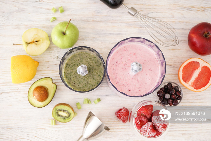 Plastic electrical hand blender and accessories with fruit on wooden background. Flat lay.