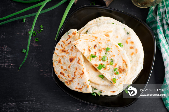 Traditional indian bread. Pita bread with green onions. Onion naan. Top view