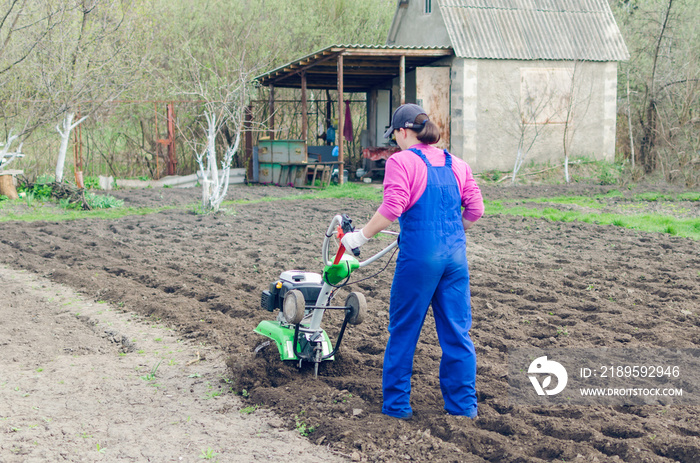 Young girl working in a spring garden with a cultivator