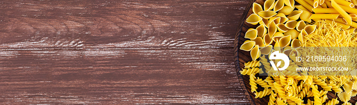 Different dry pasta on a wooden background. Top view. Banner