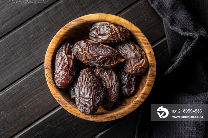 Dried dates fruit in wooden bowl.