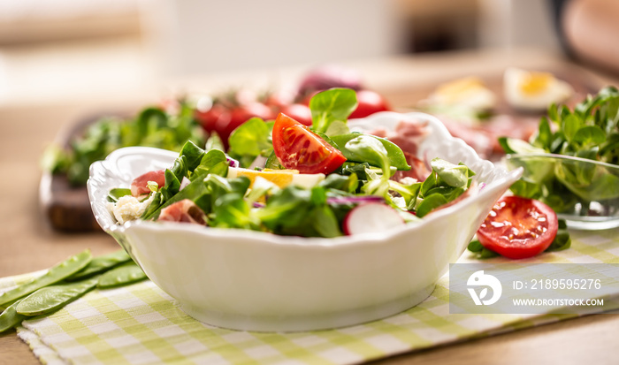 Fresh spring salad with green leaves tomatoes egg radish red onion young peas prosciutto feta cheese