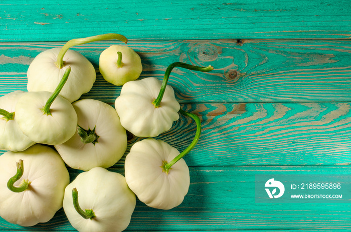 Young white patisons with green tails lie on a wooden table. Close-up