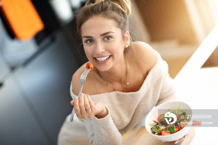 美丽微笑的女人在现代厨房吃新鲜有机素食沙拉
