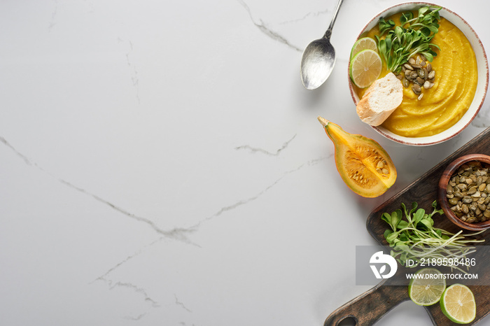 top view of delicious mashed pumpkin soup on wooden cutting board on marble surface with ingredients