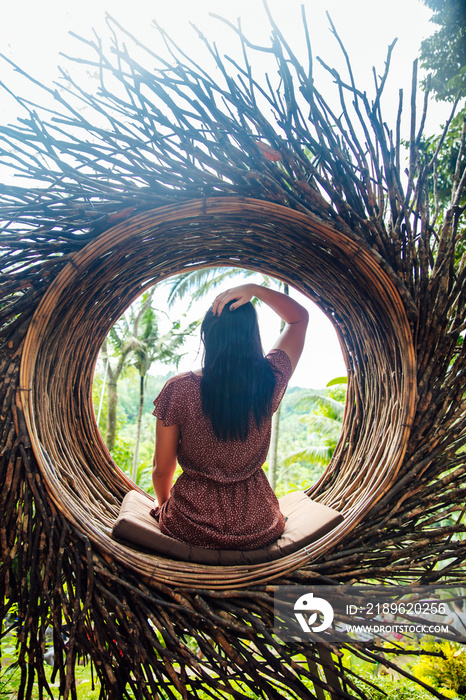 一名女游客坐在巴厘岛一棵树上的大鸟巢上