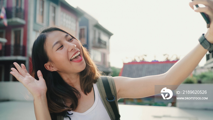 快乐美丽的年轻亚洲背包客博主女性在旅行时使用智能手机自拍