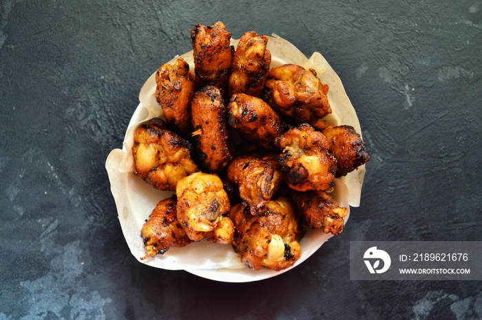 Fried chicken wings. Chicken wings on a dark background. Barbecue meat, grill. Sauce in bowls, ketch