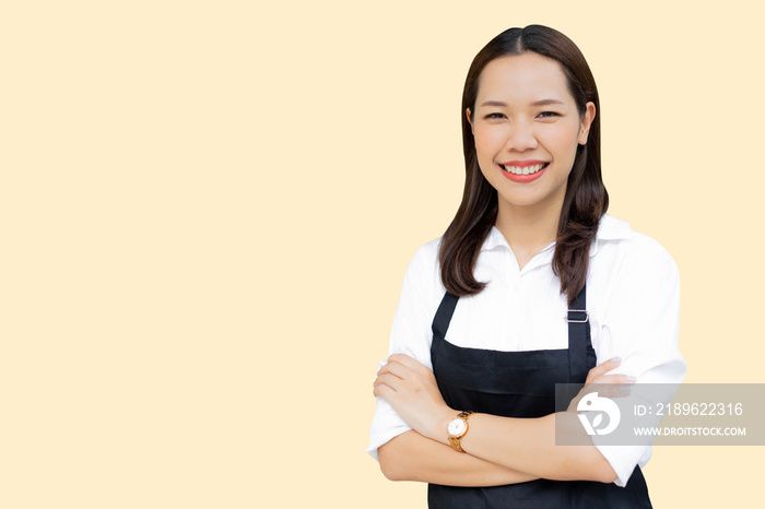 站在奶油色背景上，围着围裙的亚洲女性特写，欢迎顾客和