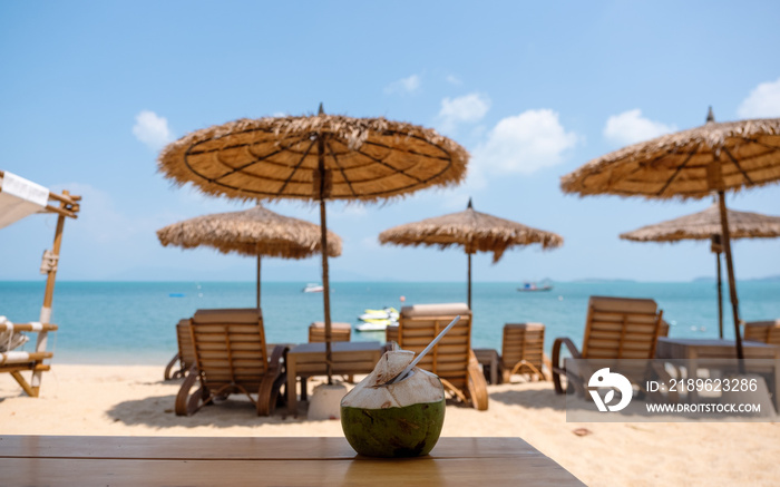 A fresh coconut on wooden table at tropical beach cafe