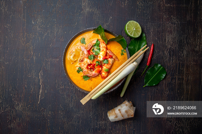 汤仁功虾，装在灰色碗里，配泰国香料，放在自给自足的托盘上，俯视图，木质背景。