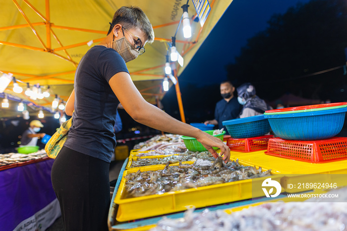 吉隆坡附近Putrajaya的街头美食夜市。一个年轻的亚洲女孩在晚上买海鲜