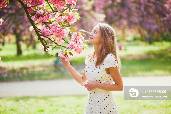 一位年轻的女士在樱花盛开的季节，在一个美好的春天，在公园里散步