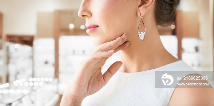 luxury and people concept - beautiful woman in evening dress wearing pearl earrings over jewelry sto