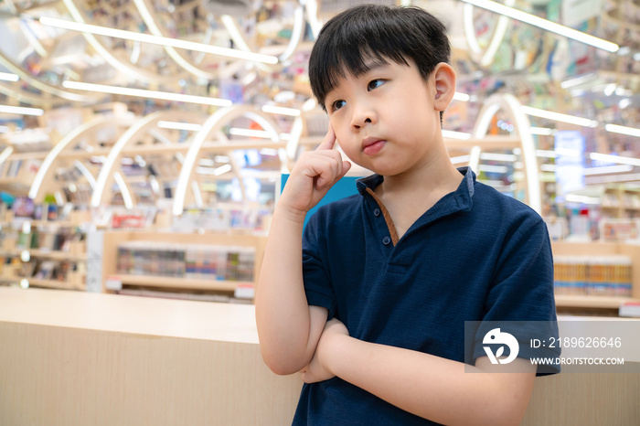 聪明的亚洲孩子站在现代漂亮的室内图书馆或有复印空间的书店里。男孩是