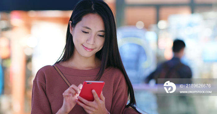 Woman check on the discount in mobile phone inside shopping mall