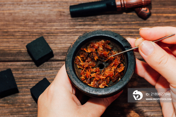 Clay bowl for hookah with coconut coals, wooden mouthpieces on a wooden background top view. Girl fi