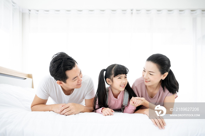 Happy asian family people leisure in bedroom together. Father and mother with daughter relaxing on b