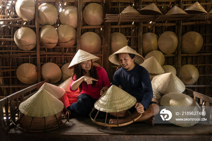 Asian couple traveler craftsman making the traditional vietnam hat in the old traditional house in A